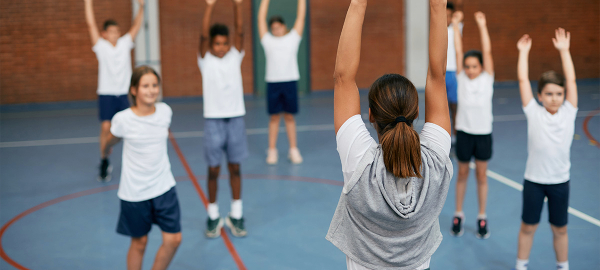 A photo of a teacher instructing young students during a physical activity class.