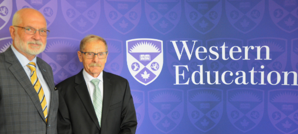 Steve Baker (left) and John Smallwood (right) stand in front of a Western Education banner.