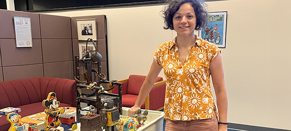 Ala Krivov standing next to a cart full of toys from the 1950s