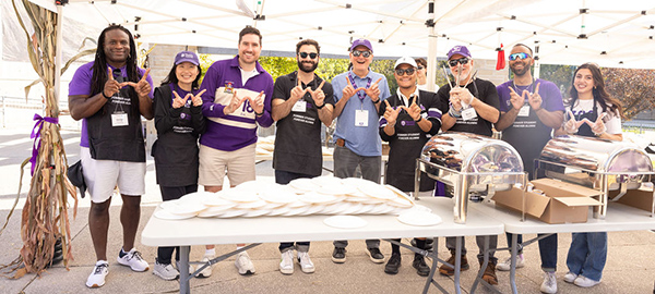 Alumni volunteers posing while serving students pancakes