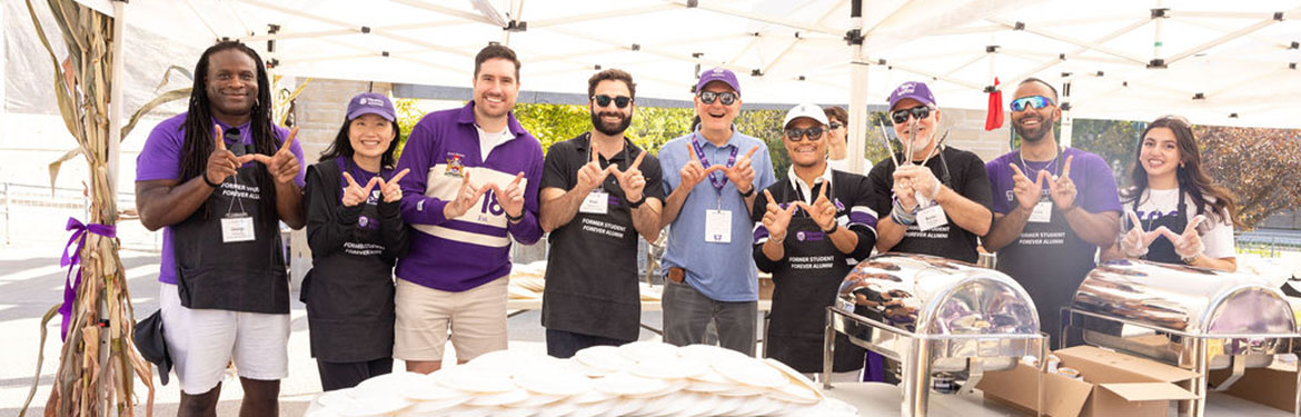 Alumni volunteers posing while serving students pancakes